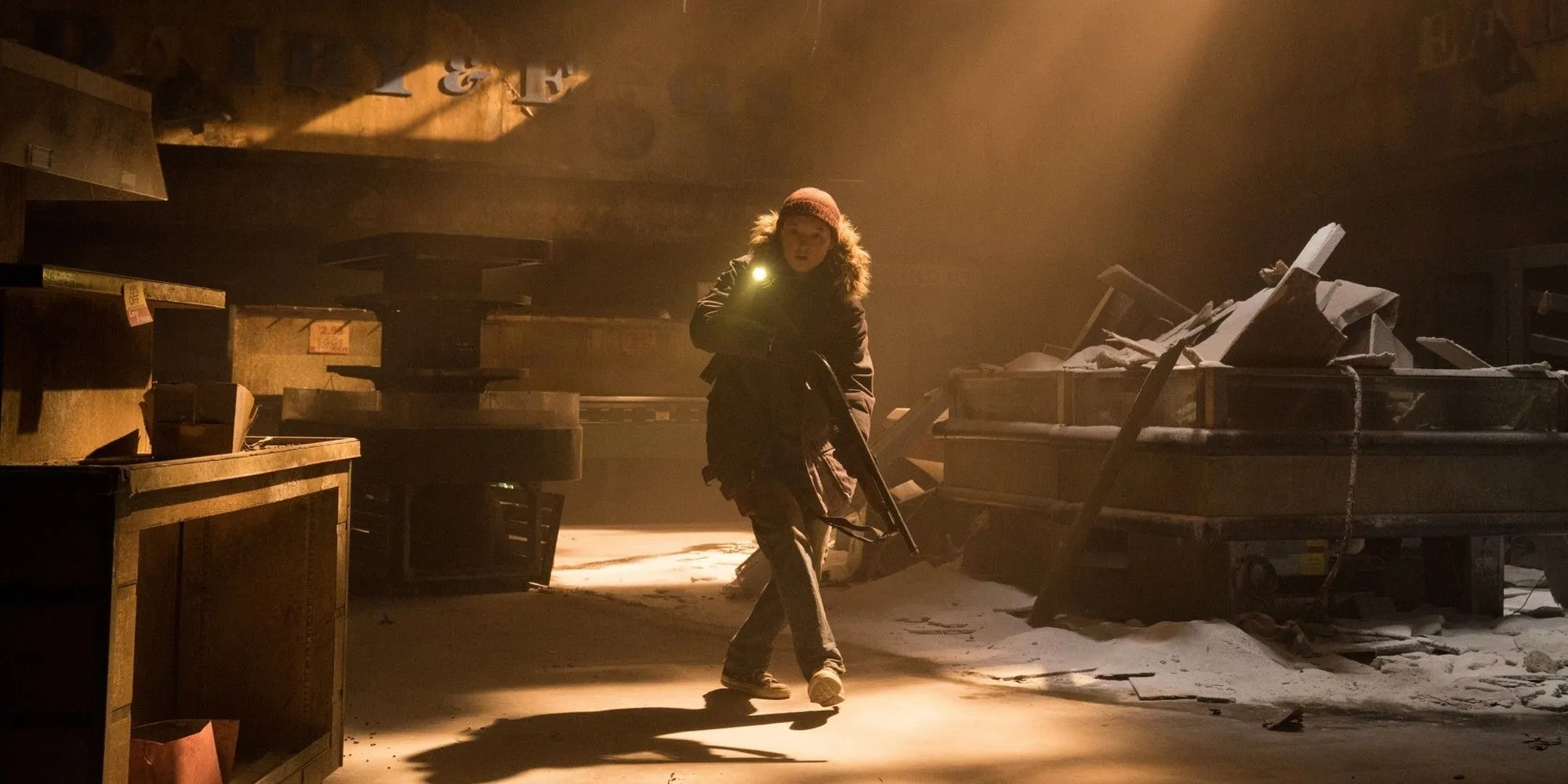 Ellie (Bella Ramsey) thận trọng di chuyển trong một tòa nhà bỏ hoang ở The Last of Us mùa 2, với khẩu súng trên tay