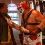 Sweet Tooth kề mã tấu đẫm máu vào ngực John Doe trong series Twisted Metal